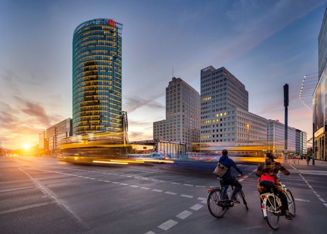 a city street with people riding bicycles and buildings in the background