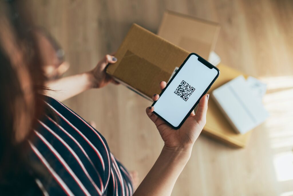 Photo to illustrate RMA, return merchandise authorization. Woman with a package and a QR code.